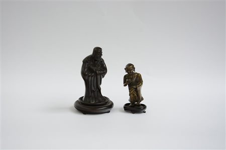Due piccoli bronzi raffiguranti Daruma e un monaco tibetano con basi in legno...