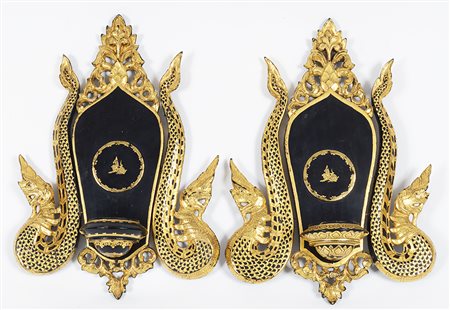Coppia di appliques in legno laccato nero e oro, di forma a scudo, con cimasa...