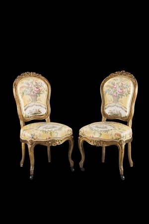 Due sedie in legno intagliato, laccato e dorato a volute, foglie e fiori,...