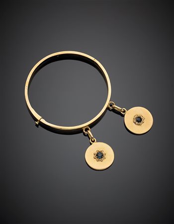 Bracciale rigido in oro giallo con due charms a medaglia entrambi centrati da...