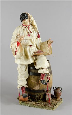 Scultura in legno e stoffa raffigurante Pulcinella sulla botte. H. cm. 50.