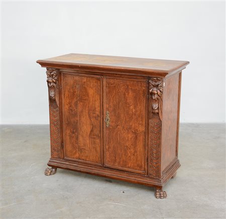 Credenza lastronata in noce a due ante sul fronte. Montanti scolpiti a...