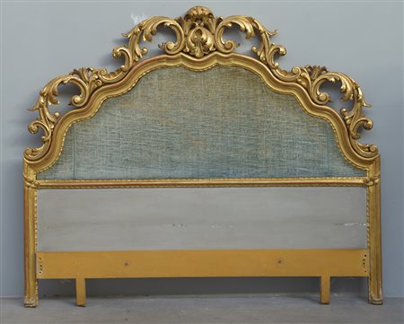 Letto in legno laccato e dorato con testata riccamente scolpita a volute e...