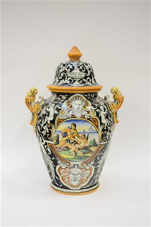 Grande vaso biansato in ceramica decorato a volute con putti e mascheroni su...