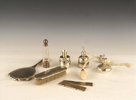 Set toletta in argento composto da otto oggetti, fogge e misure diverse.