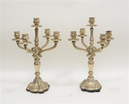 Coppia di candelabri a cinque fiamme in argento con struttura centinata....