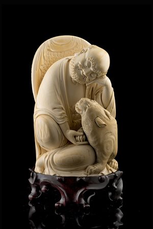 Scultura in avorio raffigurante monaco in posizione seduta accompagnato da...