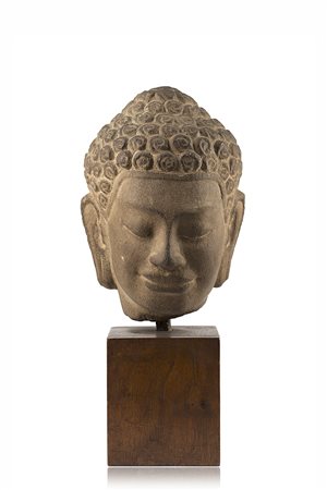 Piccola testa in pietra con base in legno (difetti)Cambogia, secolo X(h. 19...
