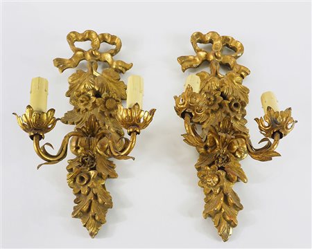 Paio di appliques in legno dorato e metallo dorato a 2 luci. H. cm. 44.