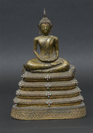 Scultura in bronzo raffigurante Buddha seduto su base a più livelli decorata...