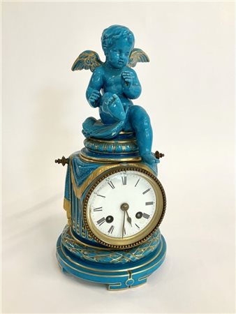 ANONIMO, Francia. Orologio da tavolo in porcellana celeste sormontato da putto