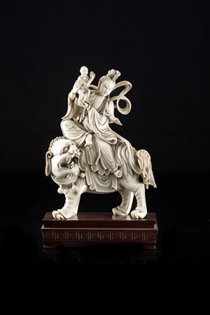 Scultura in avorio raffigurante Guanyin su leone buddista, base in legno. 
Cina