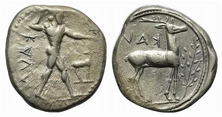 Bruttium, Kaulonia, Stater, ca. 475-425 BC. AR (g 7,90; mm 22; h 3). KAVΛ (retrograde), Nude Apollo walking r., holding branch, holding small running daimon on outstretched arm; before, stag standing r., head turned back; Rv. KAV[