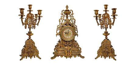 Trittico composto da coppia di candelieri e orologio in bronzo dorato....