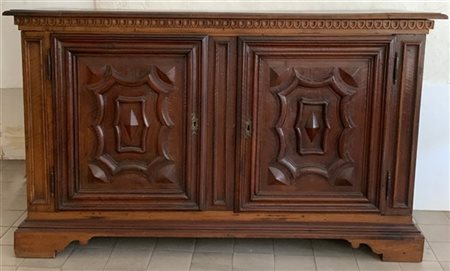 Antica credenza a due ante pannellate con decori aggettanti, fianchi bugnati e