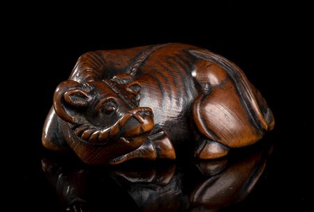 NETSUKE IN LEGNO DI BOSSO CON BUE SDRAIATO 
Giappone, periodo Edo, XIX secolo
