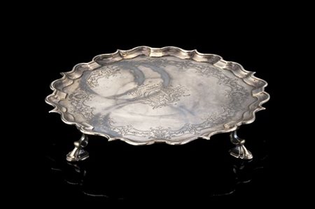 Salver in argento con bordo sagomato, poggiante su quattro piedi stilizzati. In