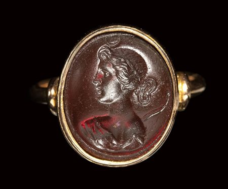 A dark red glass intaglio set in a gold ring. Bust of Diana. <br><br>19th century.