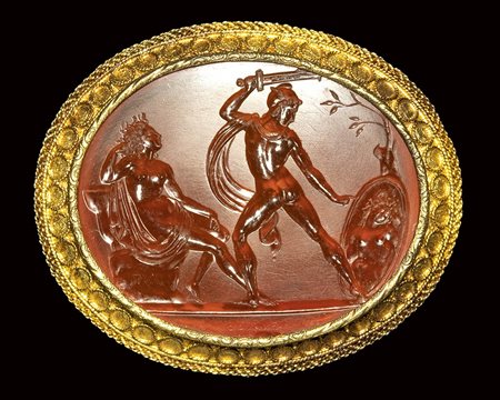 A fine neoclassical  carnelian intaglio signed Gnaios, set in a gold brooch. Perseus cutting the head of Medusa. 19th century.