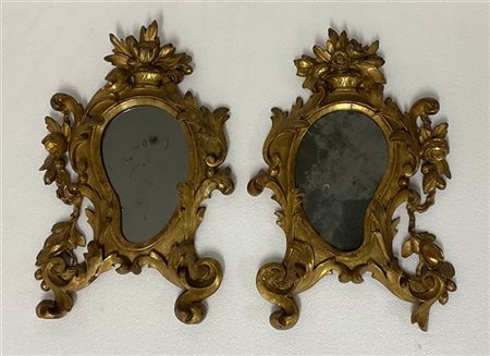 Due specchiere sagomate in legno intagliato e dorato decorate a volute fogliate