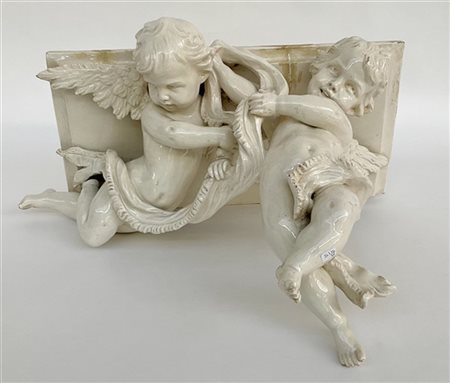 Mensola in ceramica bianca con sostegno a putti. Marcata sul piano con "N" coro