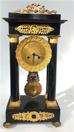 Orologio a portico in legno ebanizzato con applicazioni in bronzo dorato. Quadr