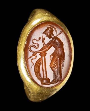 A LARGE ROMAN GOLD RING SET WITH A CARNELIAN INTAGLIO. ATHENA WITH HER WEAPONS AND A SNAKE. 