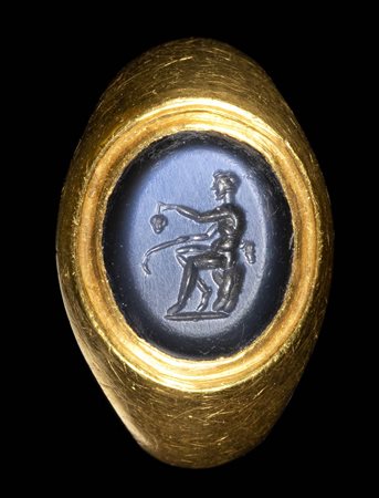 A ROMAN NICOLO INTAGLIO SET IN A GOLD RING. SEATED SATYR WITH ATTRIBUTES. 