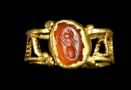 A ROMAN OPENWORKED GOLD RING WITH A CARNELIAN INTAGLIO. ANT. 