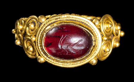 A LATE ROMAN GOLD RING SET WITH A GARNET INTAGLIO. GRASSHOPPER FACING LEFT. 