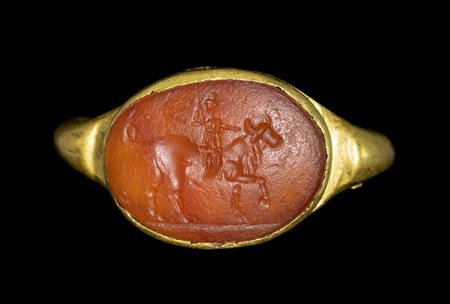 A ROMAN GOLD RING WITH A CARNELIAN INTAGLIO. A FIGURE RIDING A BULL. 