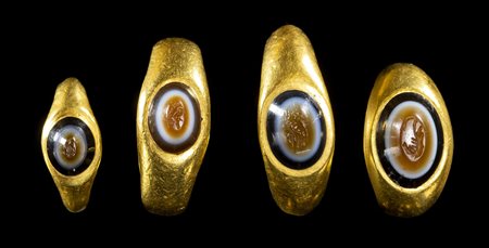 A GROUP OF 4 ROMAN GOLD RINGS SET WITH ENGRAVED THREE LAYERED AGATE INTAGLIOS. VARIOUS SUBJECTS. 