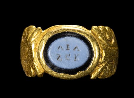 A LATE ROMAN GOLD RING SET WITH A NICOLO INTAGLIO. GREEK INSCRIPTION. 