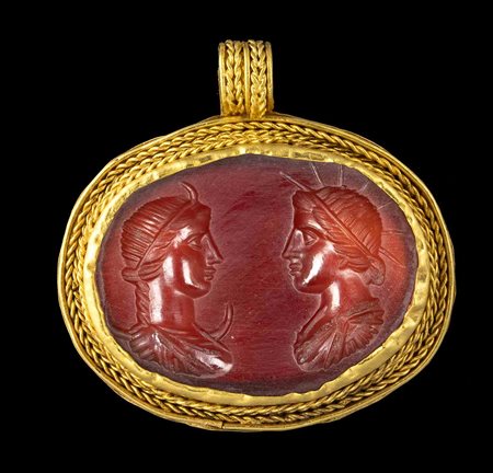 A MODERN EASTERN REVIVAL GOLD PENDANT SET WITH A LARGE CARNELIAN INTAGLIO. BUSTS OF HELIOS AND SELENE. 