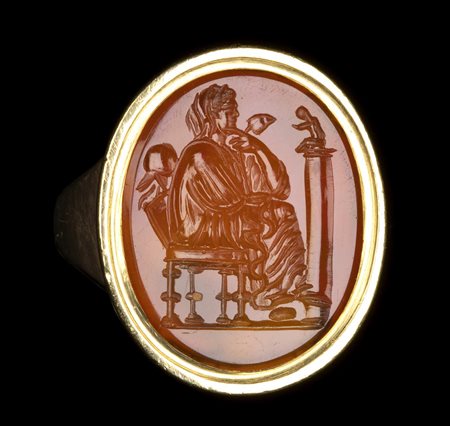 A GRAND TOUR CARNELIAN INTAGLIO SET IN A GOLD RING. SEATED MUSE. 