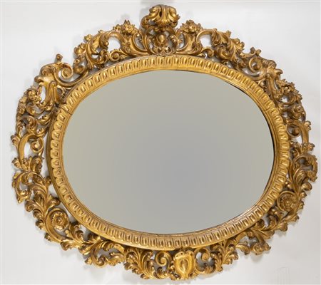 Specchiera a cartoccio ovale in legno intagliato e dorato. Toscana, XIX...