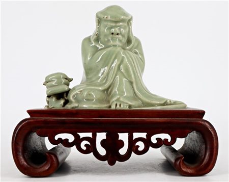 Figura di saggio assiso in porcellana celadon, poggiante su base in legno
Cina,