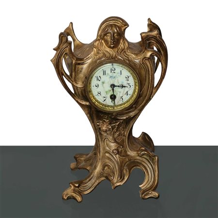 Orologio da tavolo art nuveau floreale in metallo dorato, quadrante in porcellana smaltata con figura femminile in rilievo sula cimasa