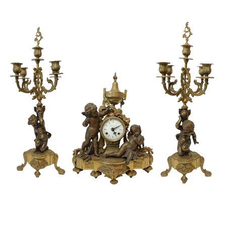 Trittico composto da orologio da tavolo in bronzo patinato oro con putti ai lati, quadrante in porce