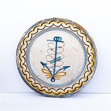 Grande piatto in maiolica con decoro a treccia in manganese sulla tesa e disegno stilizzato di un'ancora in azzurro e arancio nel cavo    Manifattura campana del XIX secolo