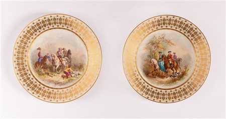 Coppia di piatti in porcellana con decori in oro di gusto secondo ottocento sulla tesa e con al cavetto dipinte scene di caccia. Sevres, fine del XIX inizi - del XX secolo   
