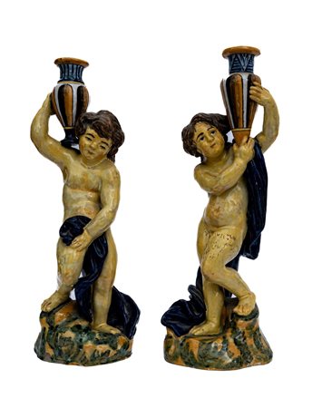 Coppia di putti tedofori in maiolica stanti a trattenere due anfore    Manifattura napoletana attiva nell'ultimo quarto del XIX secolo