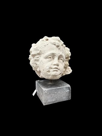 A sandstone head of a putto, mounted on a honed marble base. H.: 37 cm. excl....