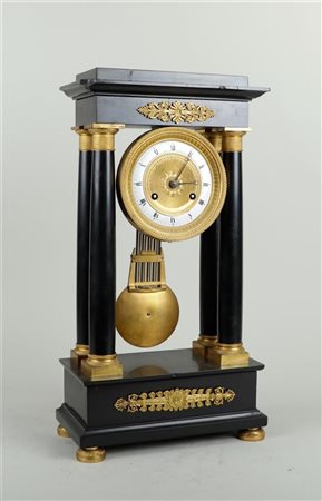 A black marble column clock on fire-gilt ball feet. Partly gilt dial with...