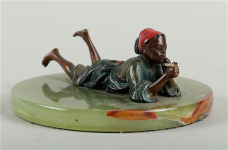 A cold painted bronze of a smoking Arab boy on a green marble disc, most...