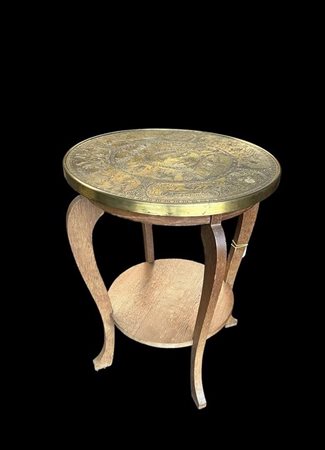 A smoking table with a chased copper top on which are depicted various...