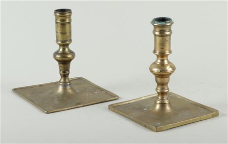 A lot of two Spanish brass candlesticks on a square base, 17th/18th century....