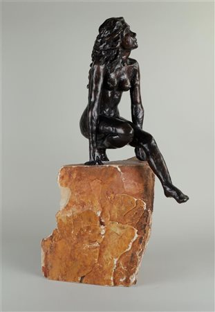 A large, dark patinated bronze sculpture of a crouching nude on a stone. 72 x...