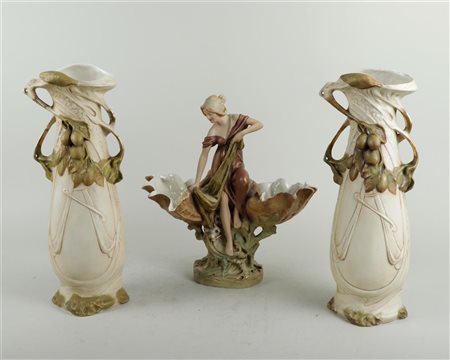 An Art Nouveau porcelain garniture depicting a fisherwoman on a rock flanked...