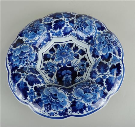 A large golobed earthenware dish with floral decoration. De porceleyne fles...